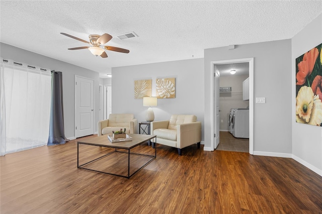 living room featuring a textured ceiling, ceiling fan, washer and clothes dryer, and wood-type flooring