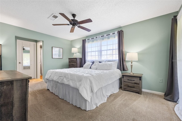 bedroom featuring light colored carpet, a textured ceiling, and ceiling fan