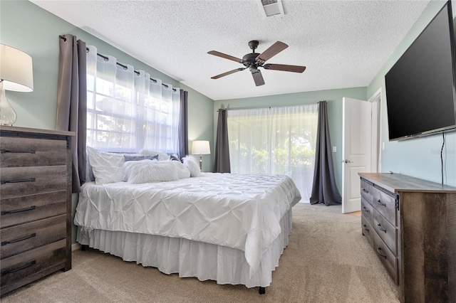 bedroom with a textured ceiling, ceiling fan, and light carpet