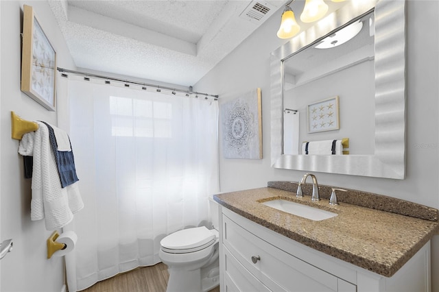 bathroom with a textured ceiling, toilet, vanity, and hardwood / wood-style flooring