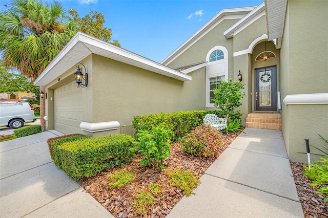 entrance to property featuring an attached garage and stucco siding