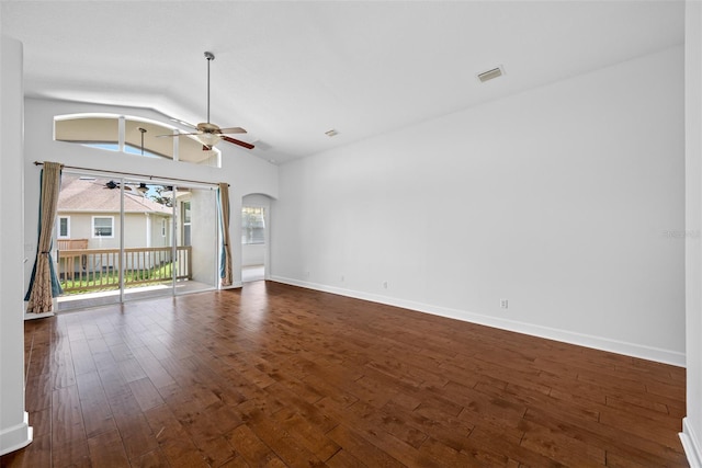 unfurnished living room featuring arched walkways, a ceiling fan, baseboards, vaulted ceiling, and dark wood-style floors