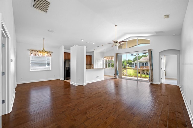 unfurnished living room featuring arched walkways, dark wood-type flooring, ceiling fan with notable chandelier, and visible vents