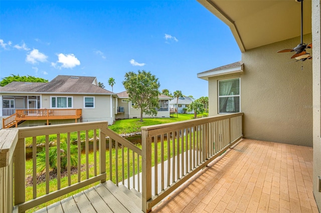 wooden terrace with a lawn, a residential view, and a ceiling fan