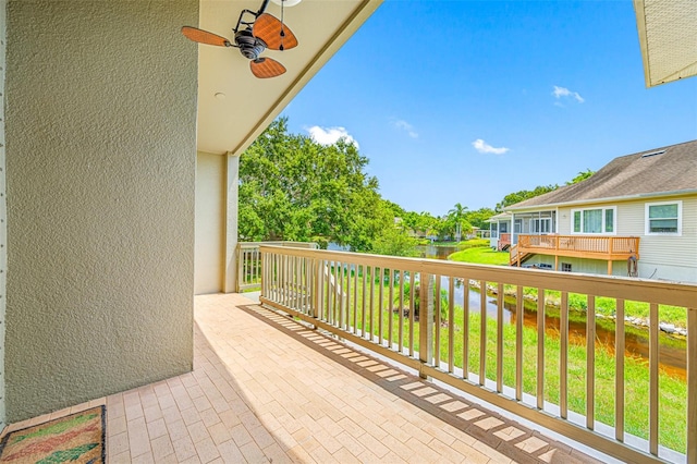 balcony with a water view and a ceiling fan