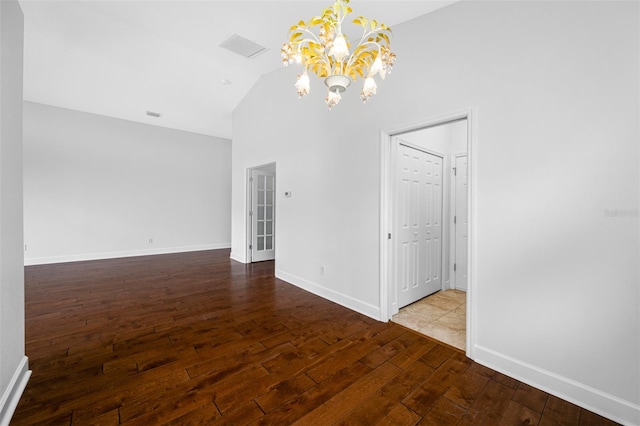 unfurnished room featuring visible vents, an inviting chandelier, wood finished floors, high vaulted ceiling, and baseboards