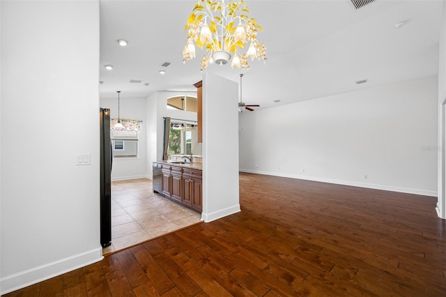 unfurnished room with lofted ceiling, light wood-style floors, a sink, baseboards, and ceiling fan with notable chandelier