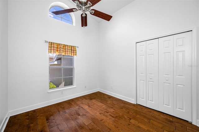 unfurnished bedroom with lofted ceiling, a closet, baseboards, and wood finished floors