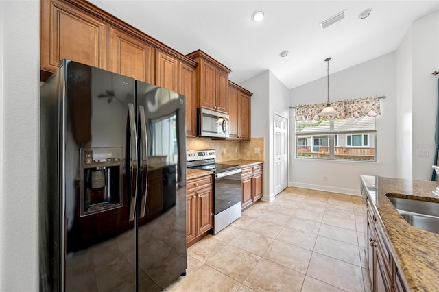 kitchen featuring lofted ceiling, light stone countertops, stainless steel appliances, and brown cabinetry