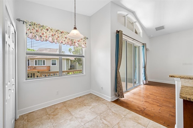 spare room with visible vents, vaulted ceiling, light wood-style flooring, and baseboards