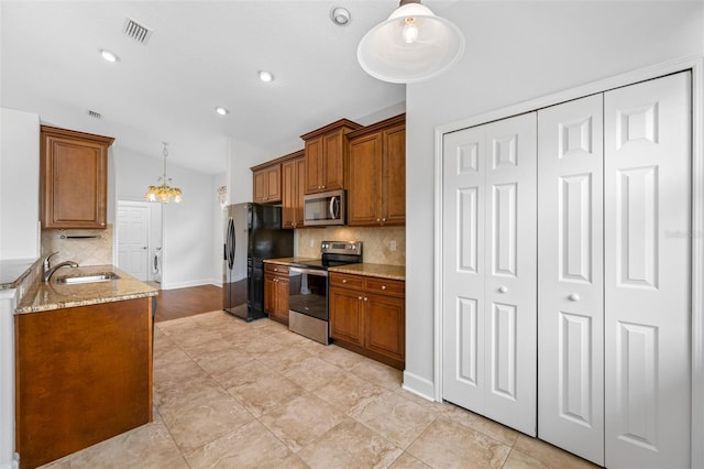 kitchen with pendant lighting, brown cabinets, visible vents, appliances with stainless steel finishes, and a sink