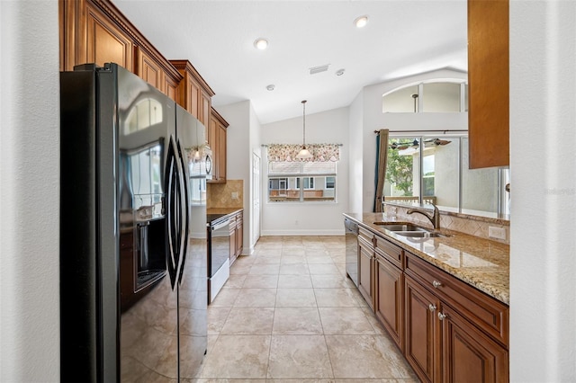 kitchen with tasteful backsplash, lofted ceiling, appliances with stainless steel finishes, brown cabinets, and a sink