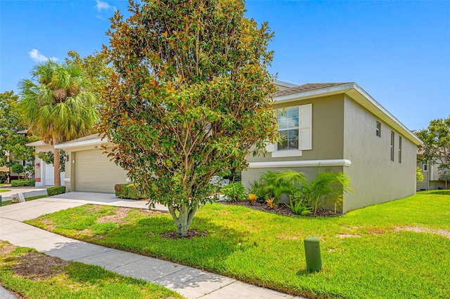 view of property hidden behind natural elements featuring a front lawn, concrete driveway, and stucco siding