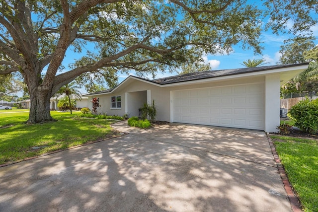 single story home with a garage, concrete driveway, a front lawn, and stucco siding