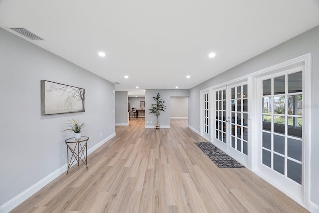 corridor featuring light wood-type flooring, french doors, visible vents, and baseboards