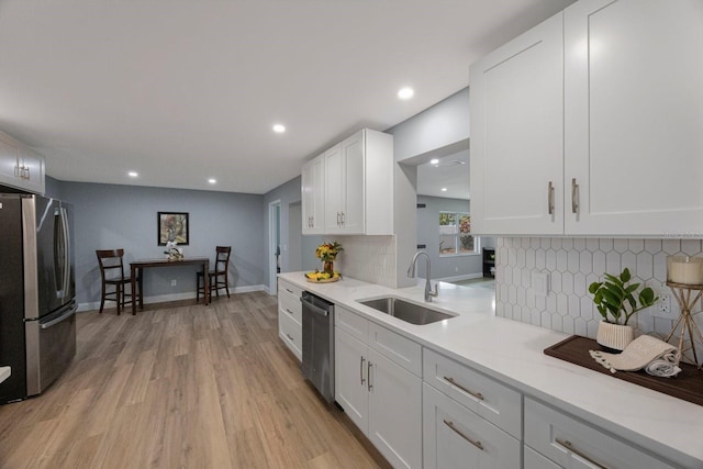 kitchen with a sink, white cabinetry, light countertops, appliances with stainless steel finishes, and light wood-type flooring