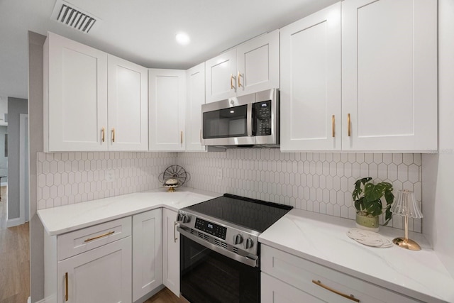 kitchen featuring light stone counters, white cabinetry, visible vents, appliances with stainless steel finishes, and tasteful backsplash