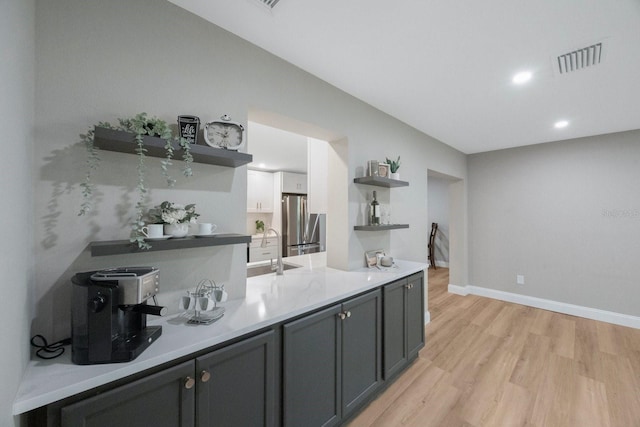 kitchen featuring visible vents, light countertops, freestanding refrigerator, open shelves, and light wood finished floors