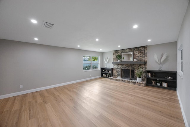 unfurnished living room featuring light wood-type flooring, a fireplace, visible vents, and baseboards