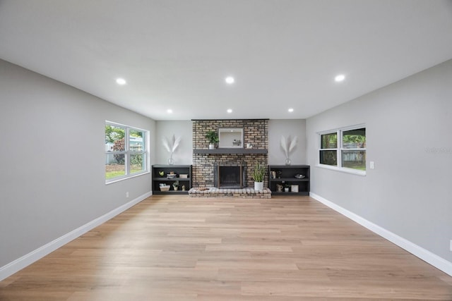 living room with light wood-style floors, a fireplace, baseboards, and recessed lighting