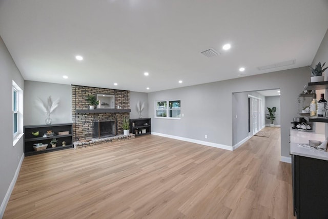 living room featuring recessed lighting, visible vents, a fireplace, and light wood-style flooring