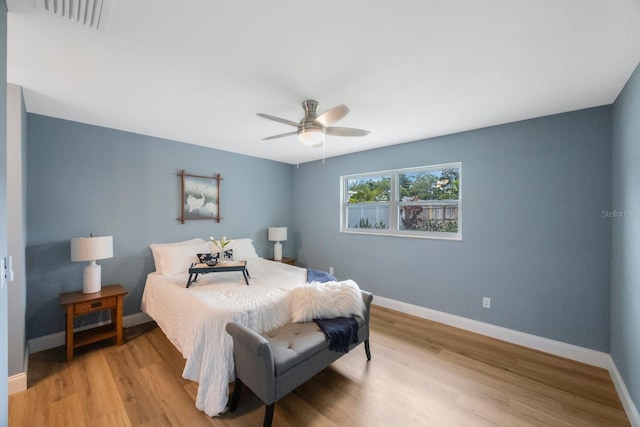 bedroom with light wood finished floors, visible vents, and baseboards