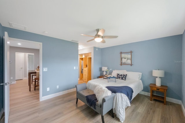 bedroom featuring light wood-style floors, attic access, visible vents, and baseboards