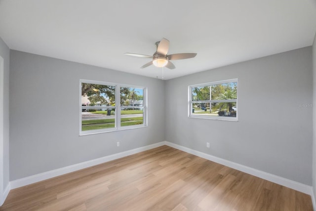 empty room with light wood-style floors, a ceiling fan, and baseboards