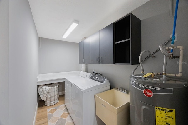 washroom with washer and clothes dryer, cabinet space, light wood-style flooring, electric water heater, and a sink