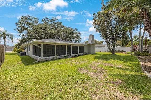 rear view of house featuring central AC unit, a sunroom, a chimney, fence, and a yard