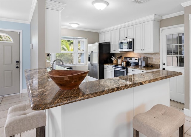 kitchen featuring light tile patterned floors, backsplash, appliances with stainless steel finishes, and ornamental molding