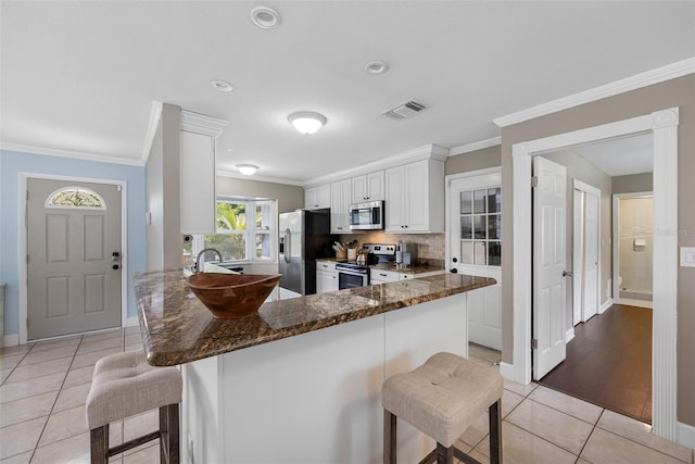 kitchen featuring white cabinets, crown molding, light wood-type flooring, stainless steel appliances, and a kitchen breakfast bar