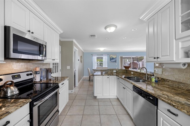 kitchen with appliances with stainless steel finishes, dark stone countertops, decorative backsplash, and sink