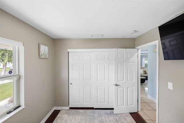 unfurnished bedroom featuring a closet, a textured ceiling, and tile patterned floors