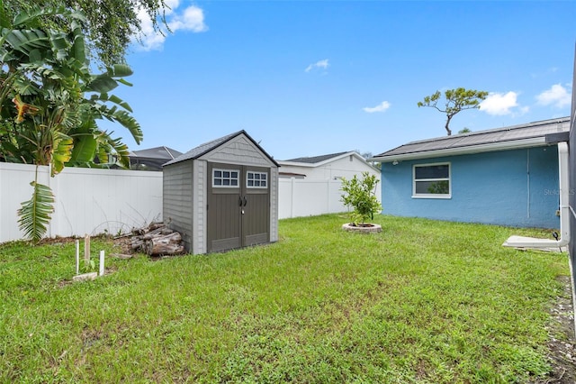 view of yard featuring a storage shed, a fenced backyard, an outdoor structure, and a fire pit