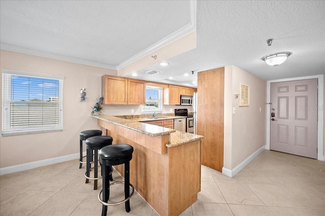 kitchen featuring ornamental molding, a peninsula, stainless steel appliances, a textured ceiling, and a sink