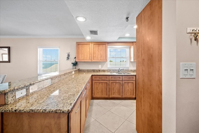 kitchen featuring visible vents, light stone countertops, a textured ceiling, a sink, and light tile patterned flooring