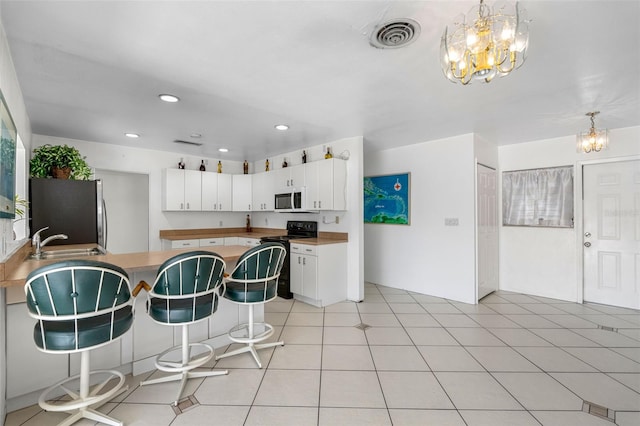 kitchen with sink, appliances with stainless steel finishes, white cabinetry, and light tile patterned flooring