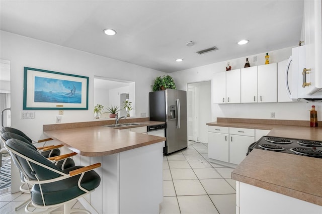 kitchen featuring light tile patterned floors, appliances with stainless steel finishes, a breakfast bar, kitchen peninsula, and sink