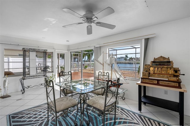 dining room featuring a water view, light tile patterned floors, and ceiling fan