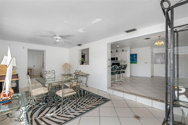 tiled dining space with ceiling fan with notable chandelier