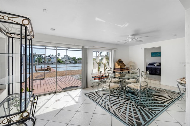 tiled dining space with ceiling fan and a water view