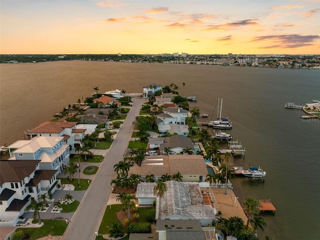 aerial view at dusk featuring a water view