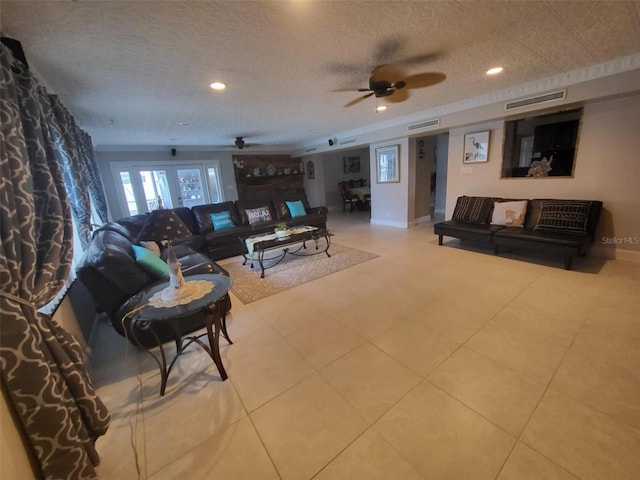 living room with ceiling fan, french doors, light tile patterned flooring, and a textured ceiling