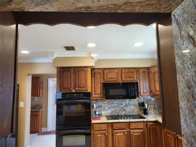 kitchen with tasteful backsplash, light stone counters, crown molding, black appliances, and light tile patterned floors