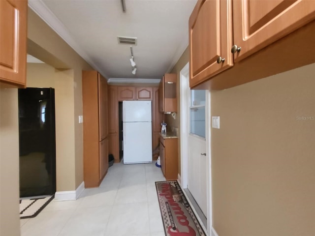 kitchen featuring rail lighting, white refrigerator, ornamental molding, and light tile patterned floors