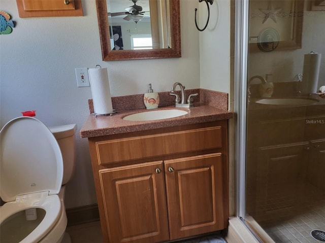 bathroom with ceiling fan, toilet, an enclosed shower, and vanity