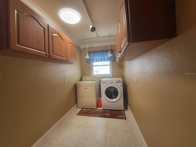 washroom featuring rail lighting, washing machine and dryer, light tile patterned flooring, and cabinets