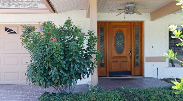 entrance to property featuring ceiling fan, covered porch, and a garage