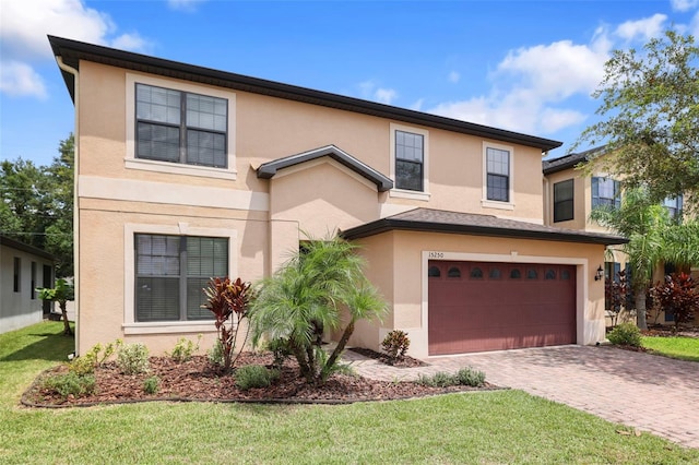 view of front of property with an attached garage, a front yard, decorative driveway, and stucco siding